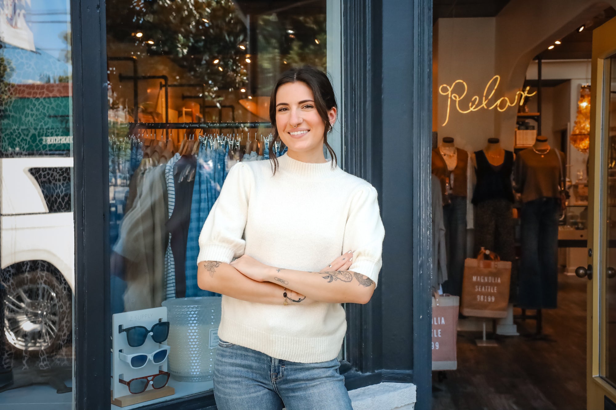 Woman standing in front of a store with 'Relax' sign and clothing display at Vixen Collection in Seattle, WA