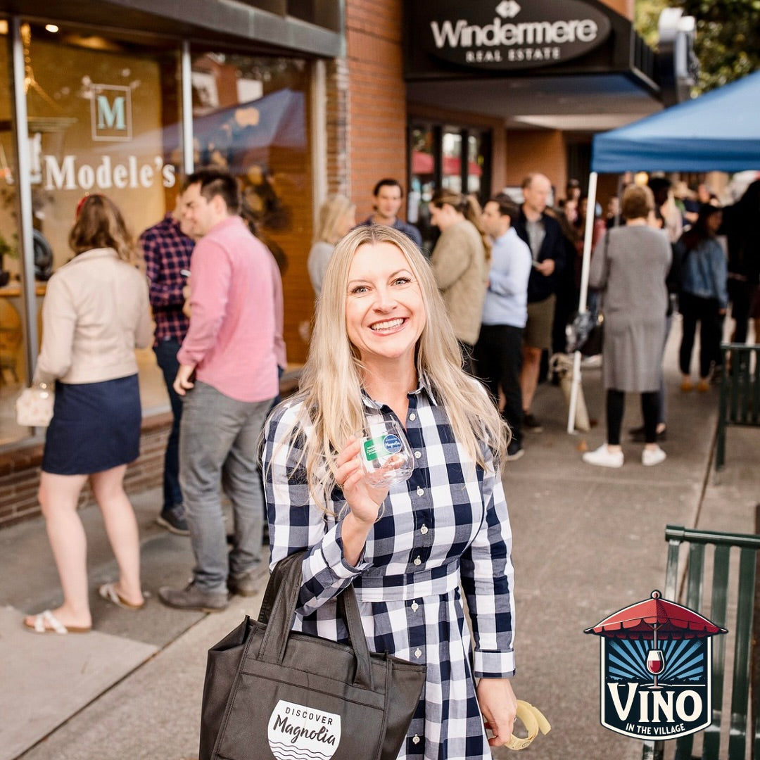 Woman holding a drink in a plaid shirt with a crowd in the background, featuring Windermere Real Estate and Modele's.