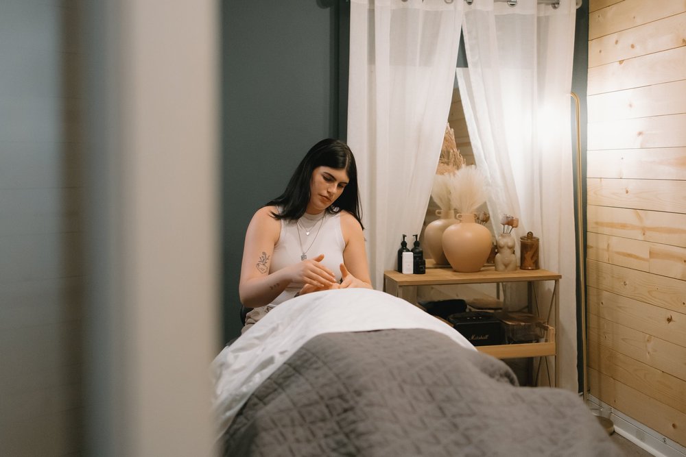 Woman receiving a massage in a spa setting with wooden walls and white curtains.