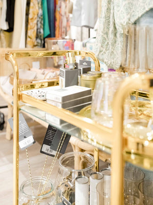Gold bar cart with jewelry and decorative items in a store setting