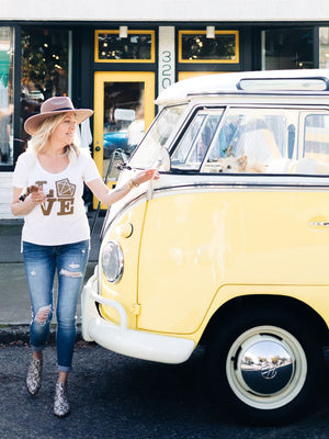 Woman standing next to a yellow vintage van with a store in the background