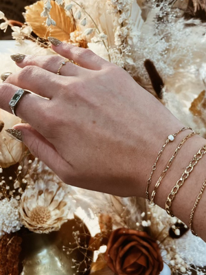 Woman's hand wearing permanent jewelry on write and fingers. 